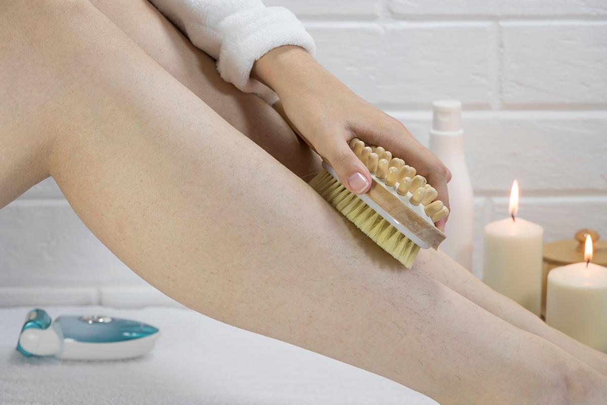 Woman exfoliating legs with a dry brush