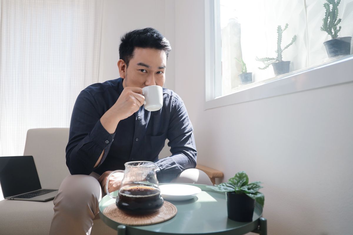 A man holds his hand out to refuse a cup of coffee