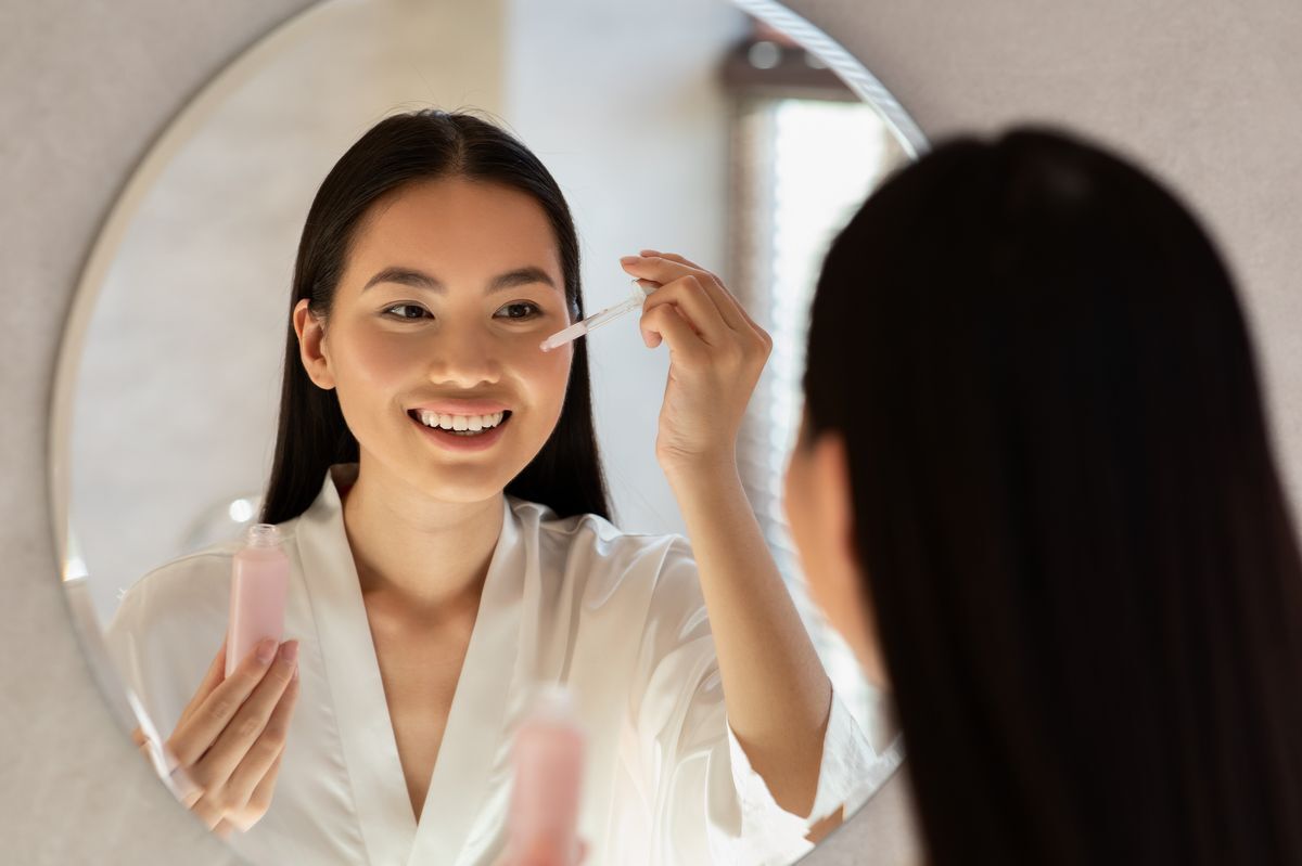 Filipino woman applying product on her face while in a bathrobe.
