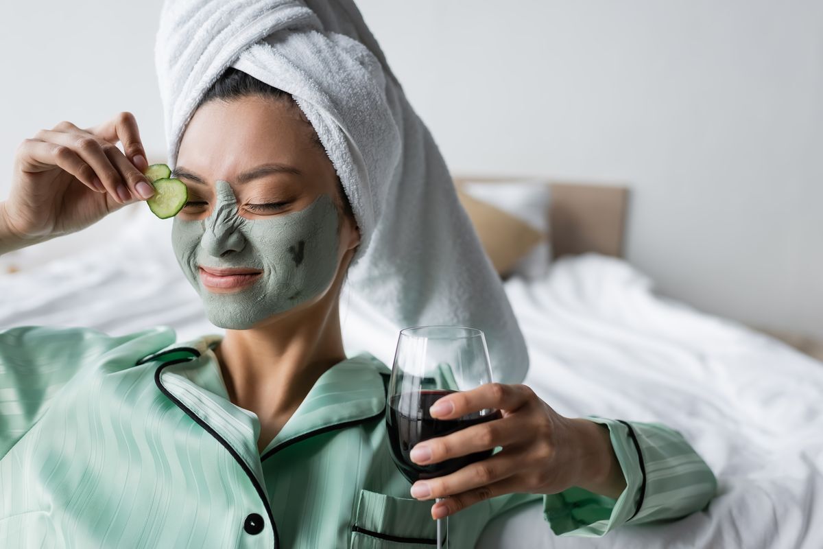 Woman in green pajamas doing a clay mask.