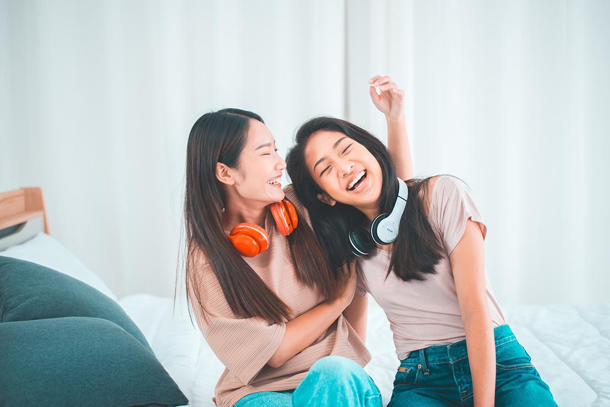 Two female Asian friends with headphones laughing