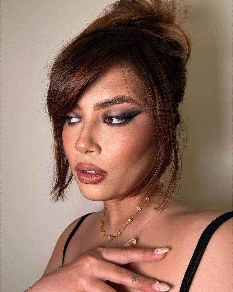 Asian woman with cat eye and shaggy red hair with bangs