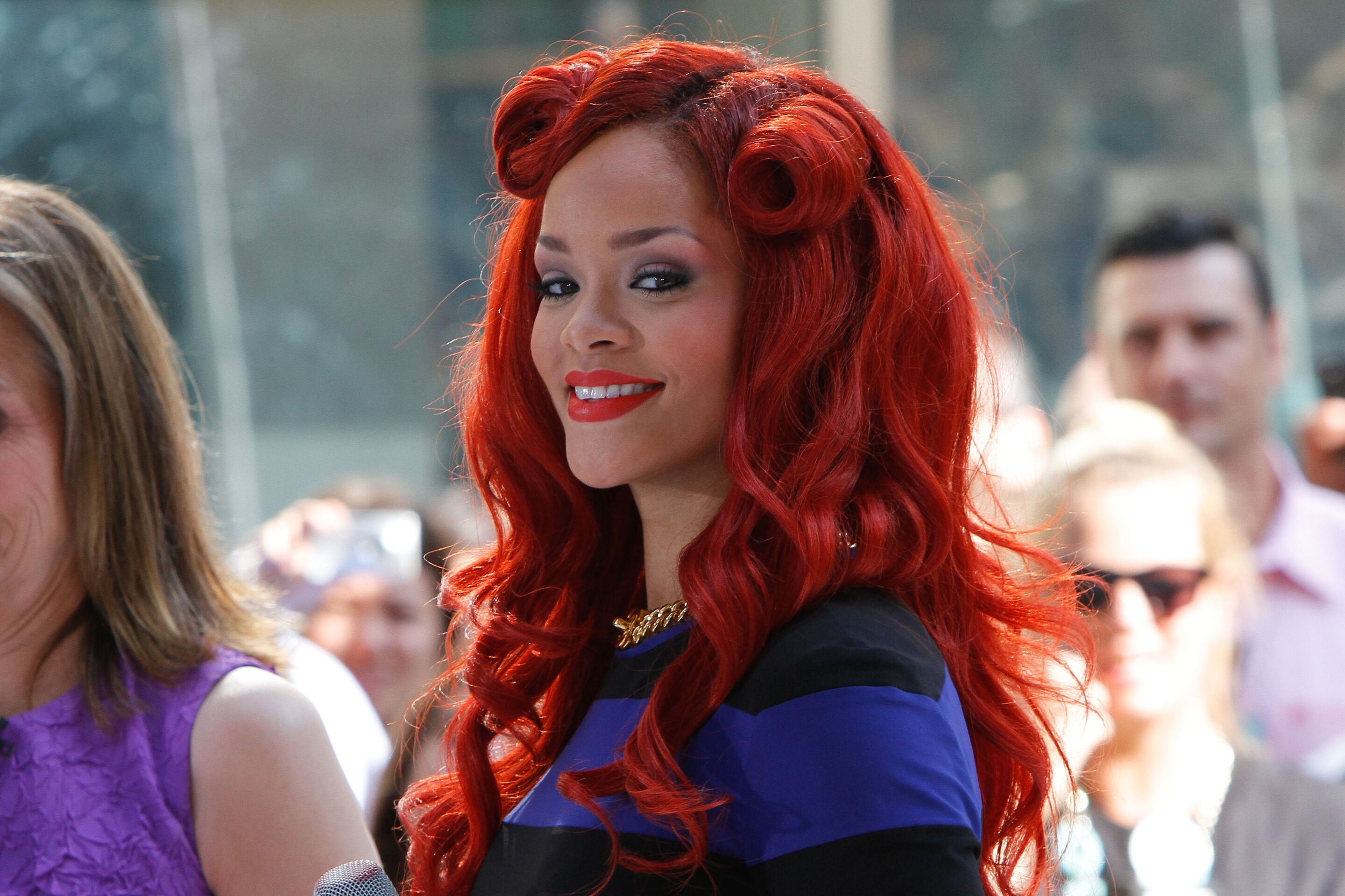 Rihanna with red hair and a blue and black striped dress