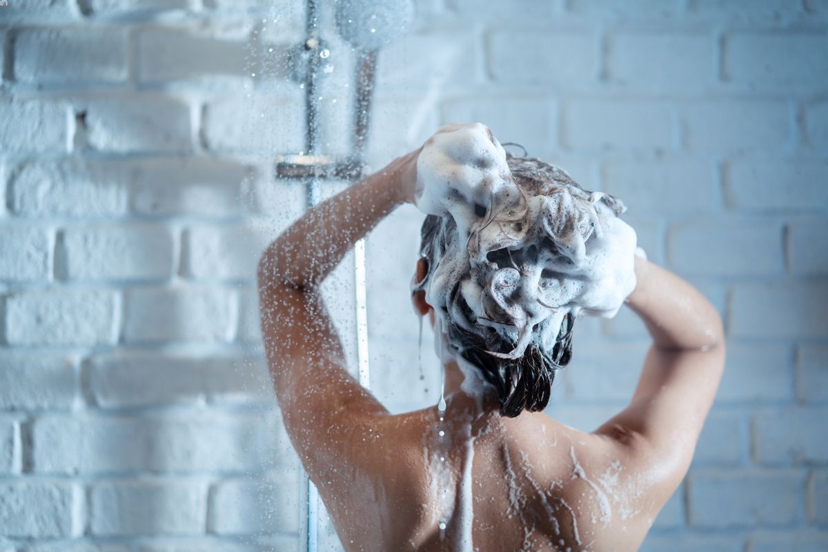 Woman washing her hair with shampoo in the shower.