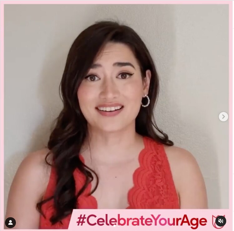 Nicole Andersson with wavy hair in a red top and hoop earrings.