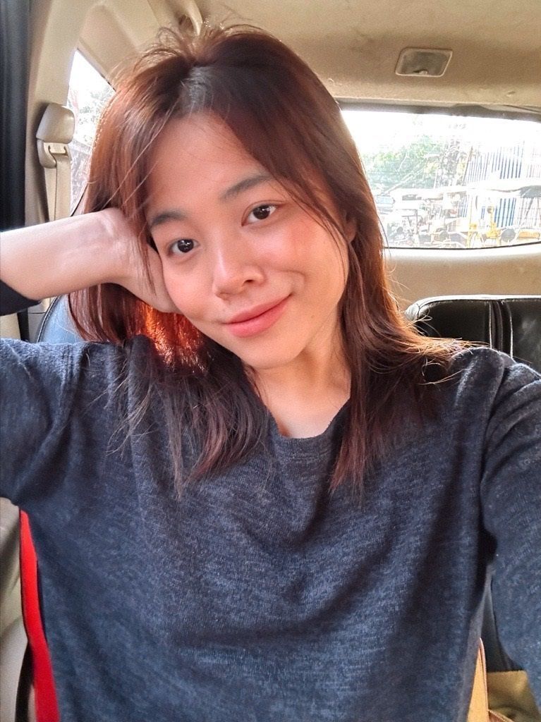 Smiling woman in black top posing inside a car.