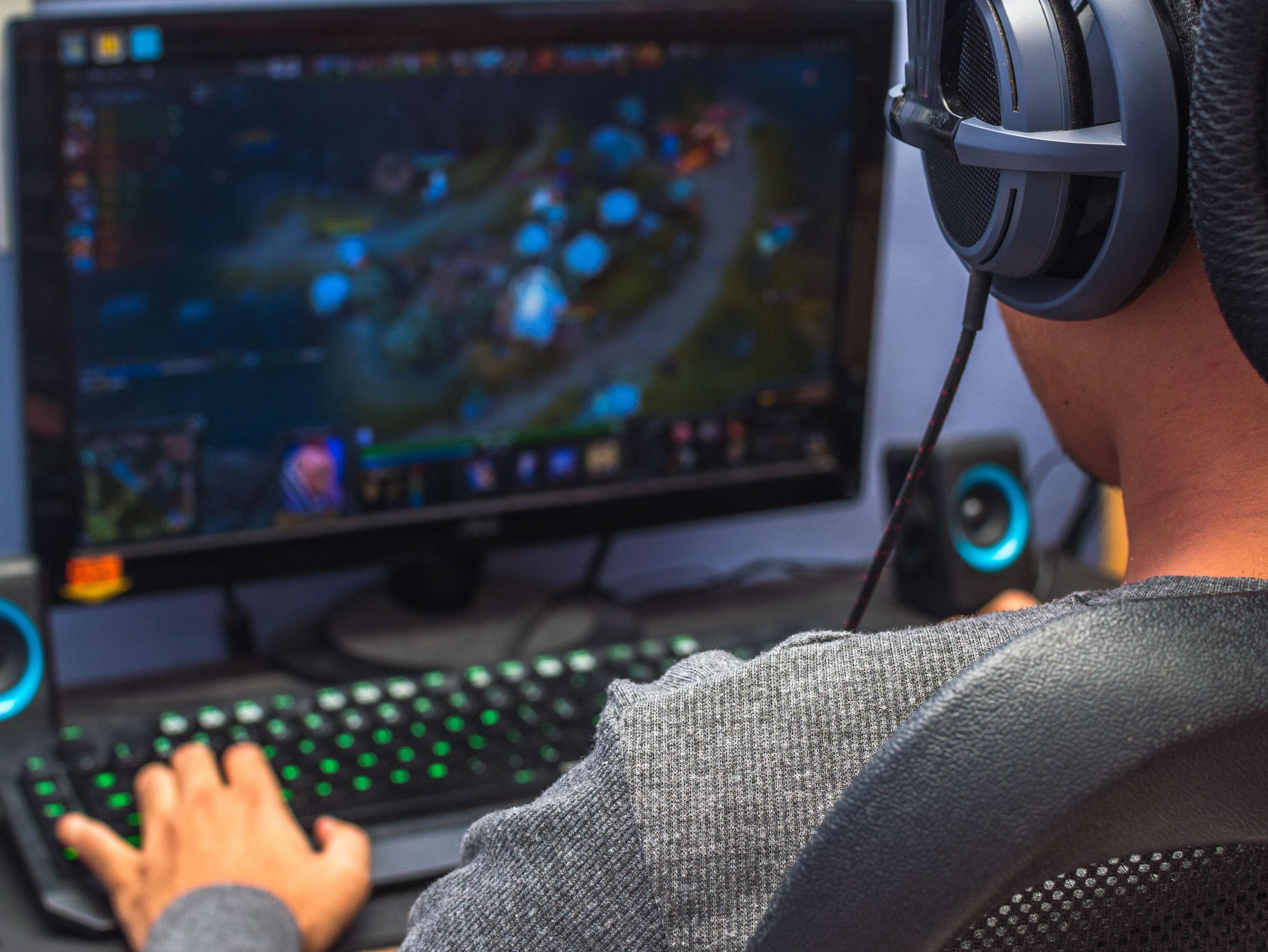 Back view of a guy wearing headphones and focusing on online gaming