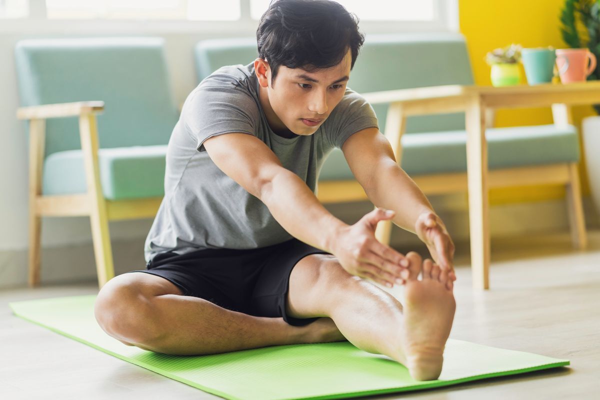 Man stretching his leg on his yoga mat.