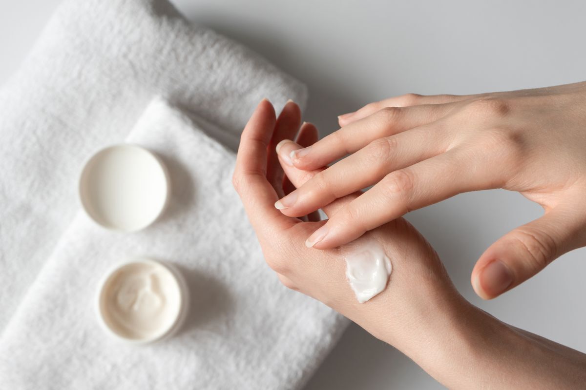 A pair of hands swatching face cream on skin.