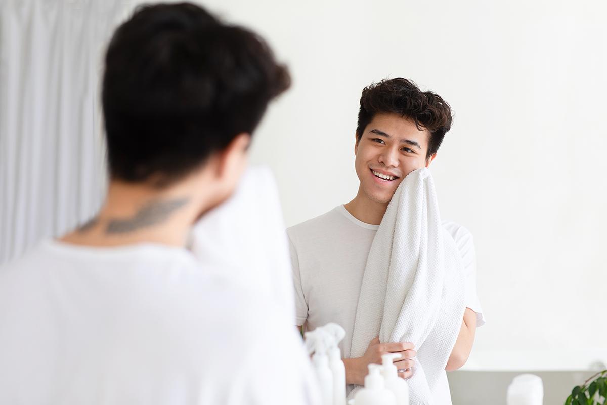 Asian man patting his face dry with a towel