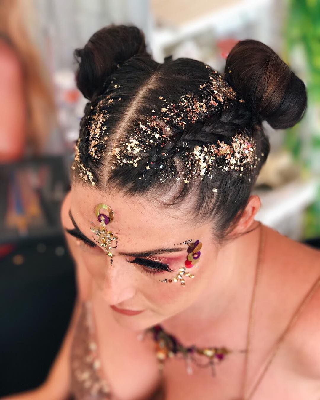 Woman with braided space buns and gold glitter covering her hair.