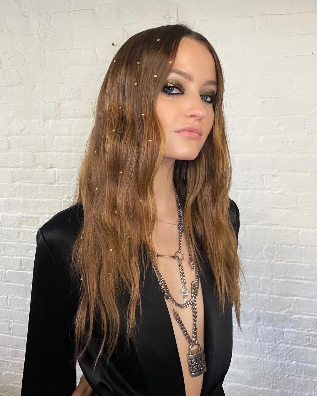 Woman with red, long hair and dazzling gems sticking on her hair.