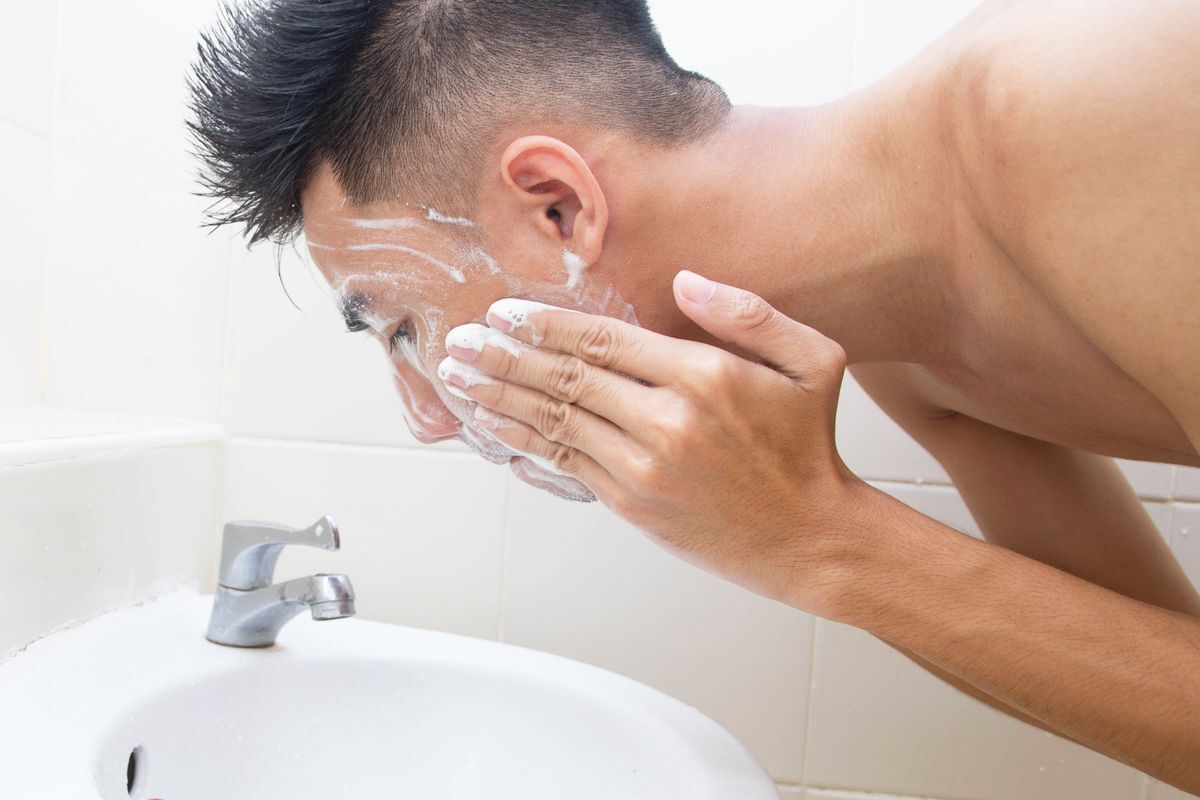 Man soaping his face in the bathroom.