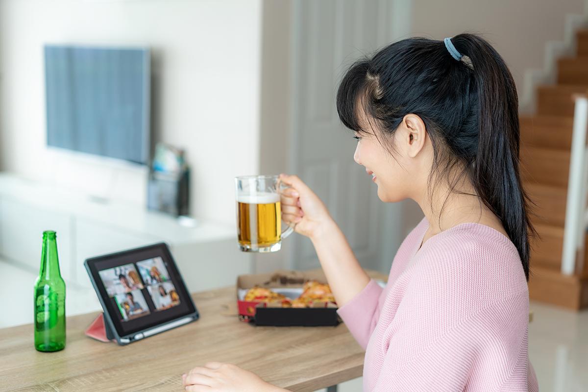 Asian woman drinking beer while video chatting