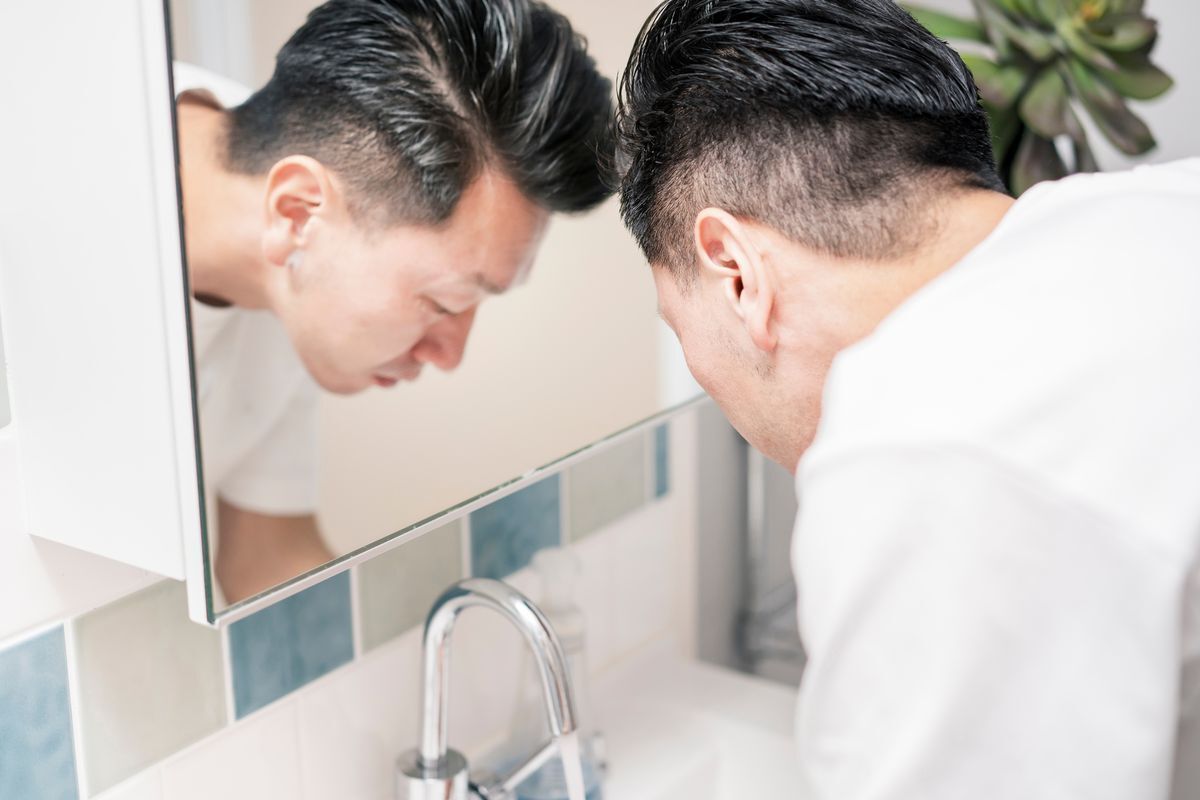 Asian man washes his face with foaming cleanser