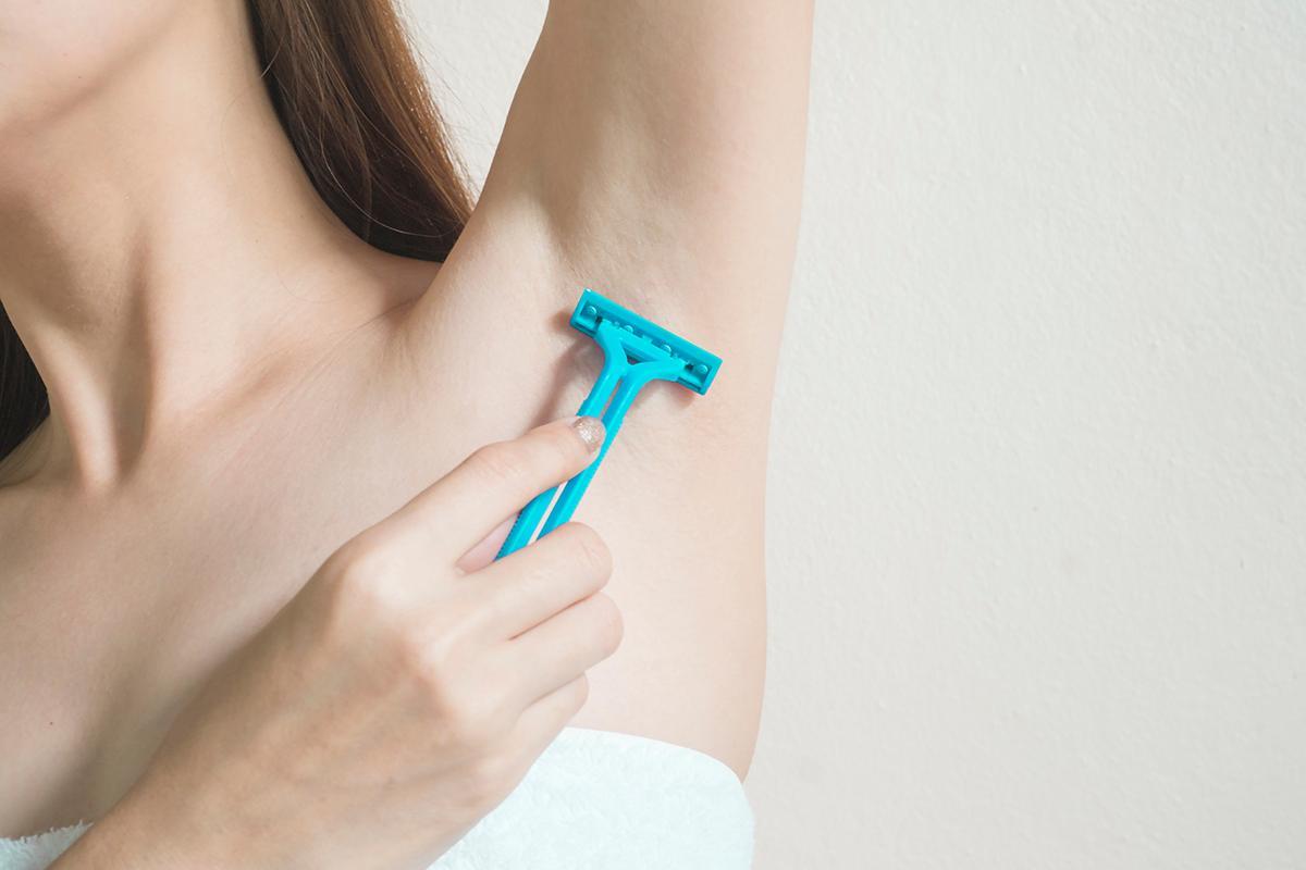 Closeup of shaving armpit with a razor