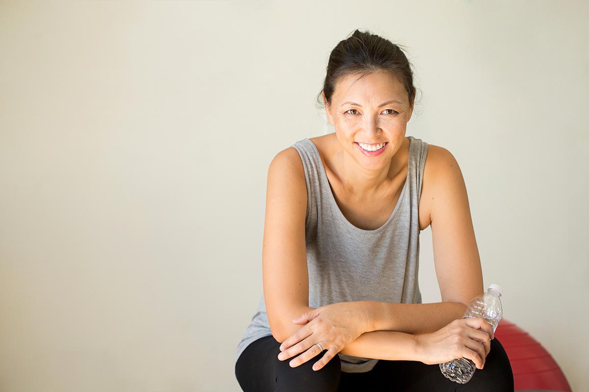 Asian woman in a gray tank top holding a water bottle