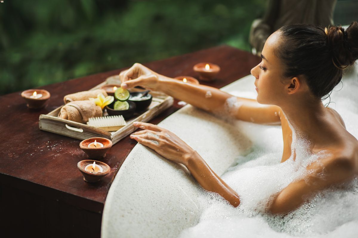 Asian woman preparing candles and aromatherapy beside the bath
