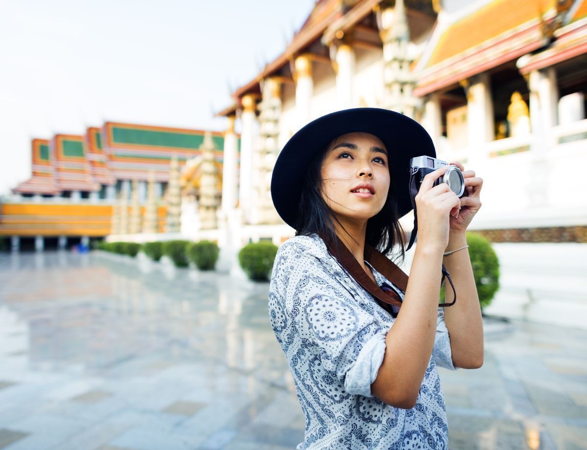 Filipino woman traveler looking upward while holding a camera against a temple