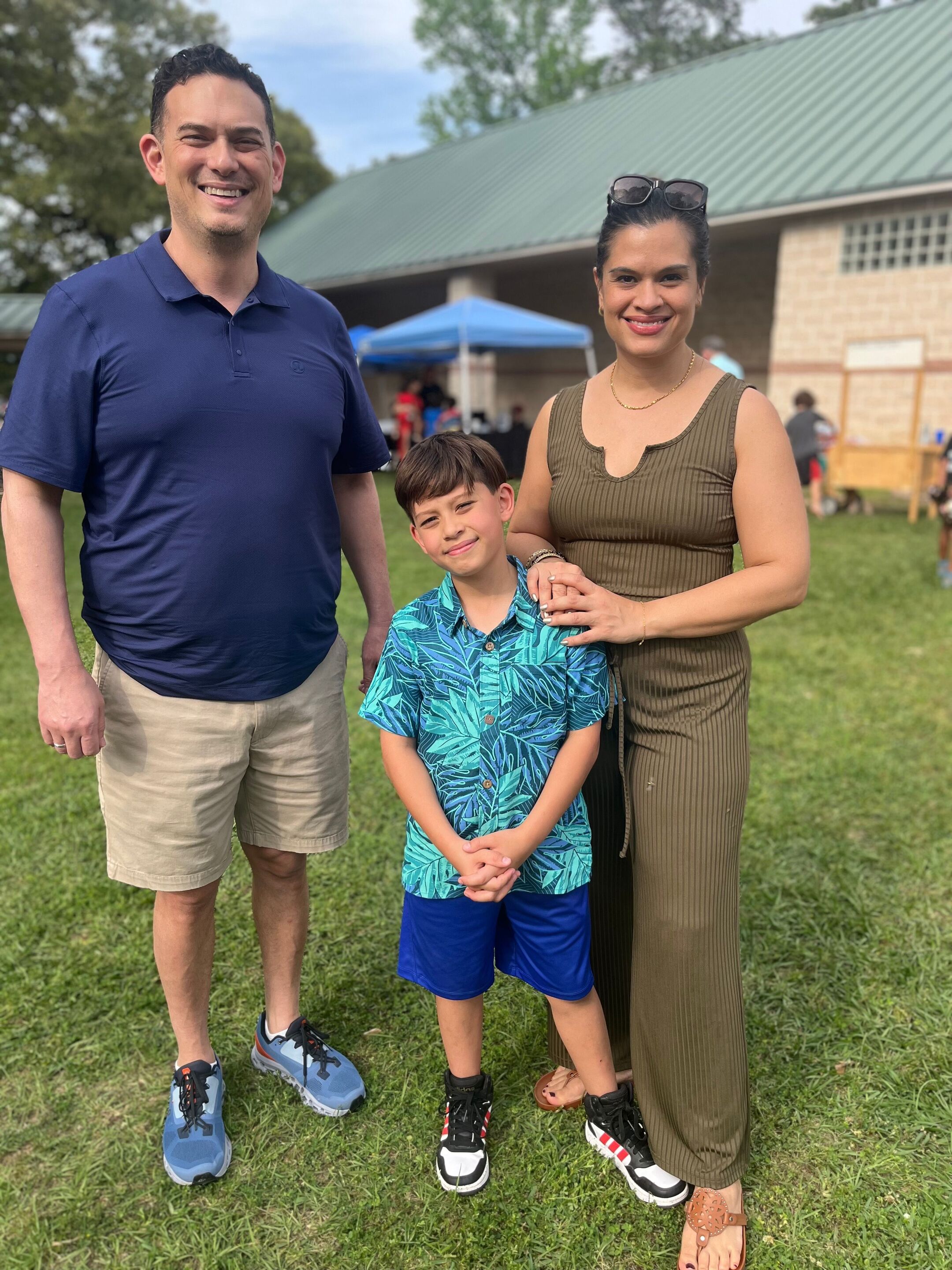 Family photo with mixed race father, mother and son smiling outdoors.