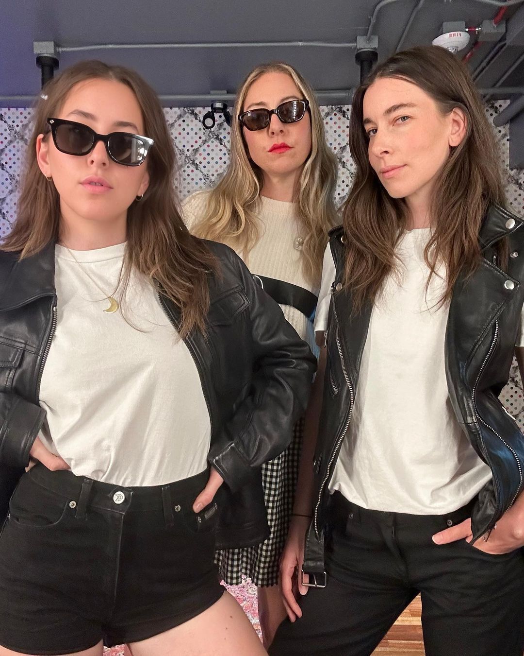 A portrait of HAIM posing together while wearing leather jackets.