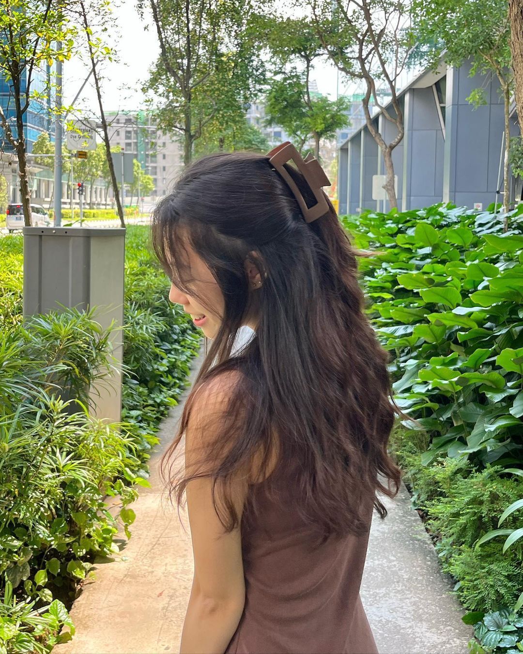 Woman with long brown hair wearing brown top and brown claw clip.