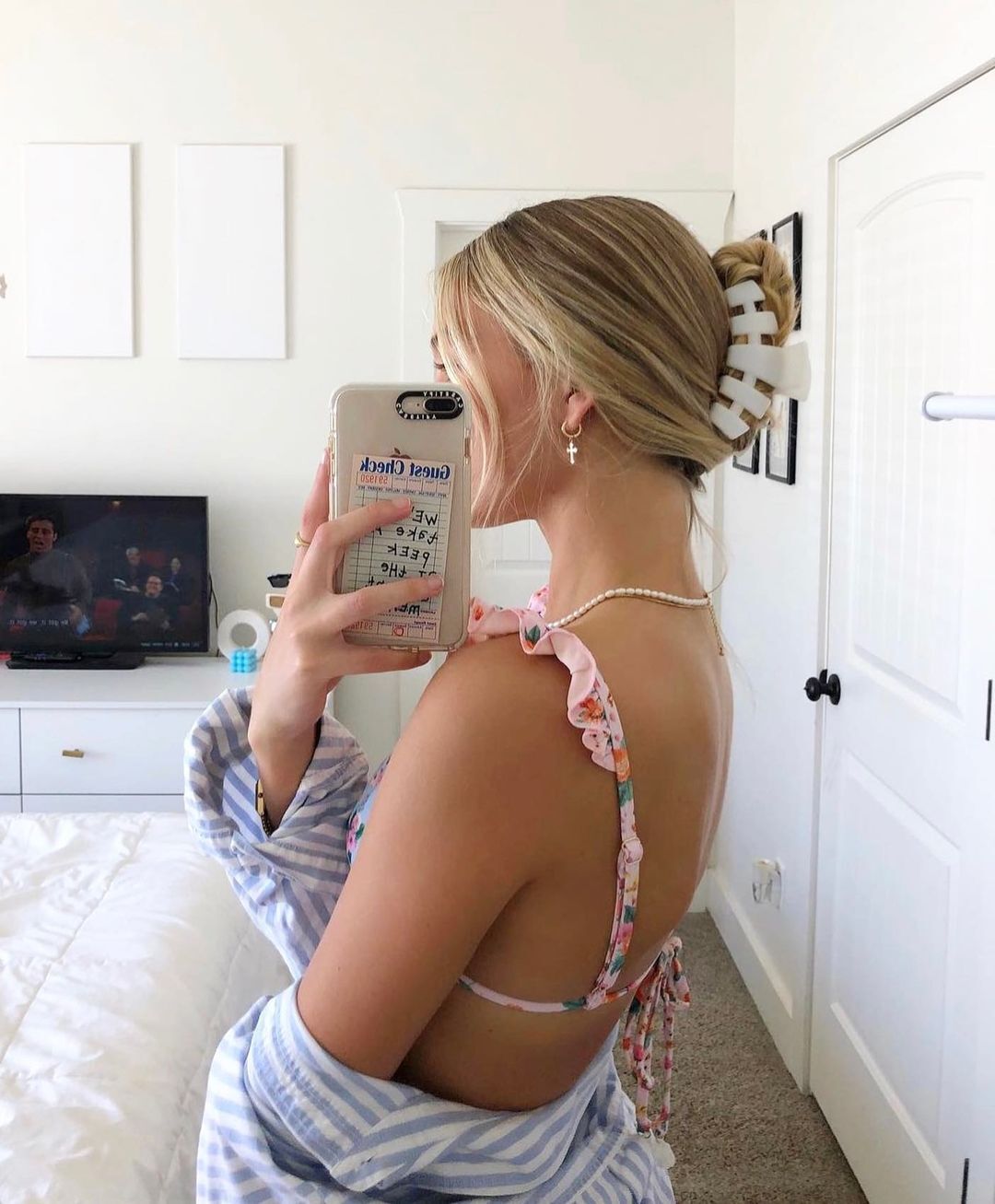Woman with blonde hair and white claw clip taking a mirror selfie.