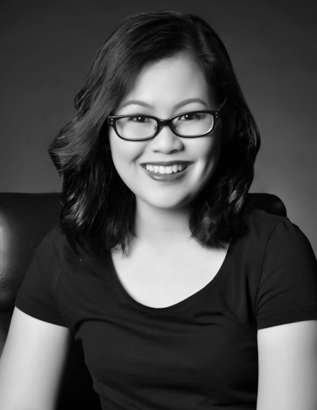 Black and white portrait of an Asian woman wearing glasses.