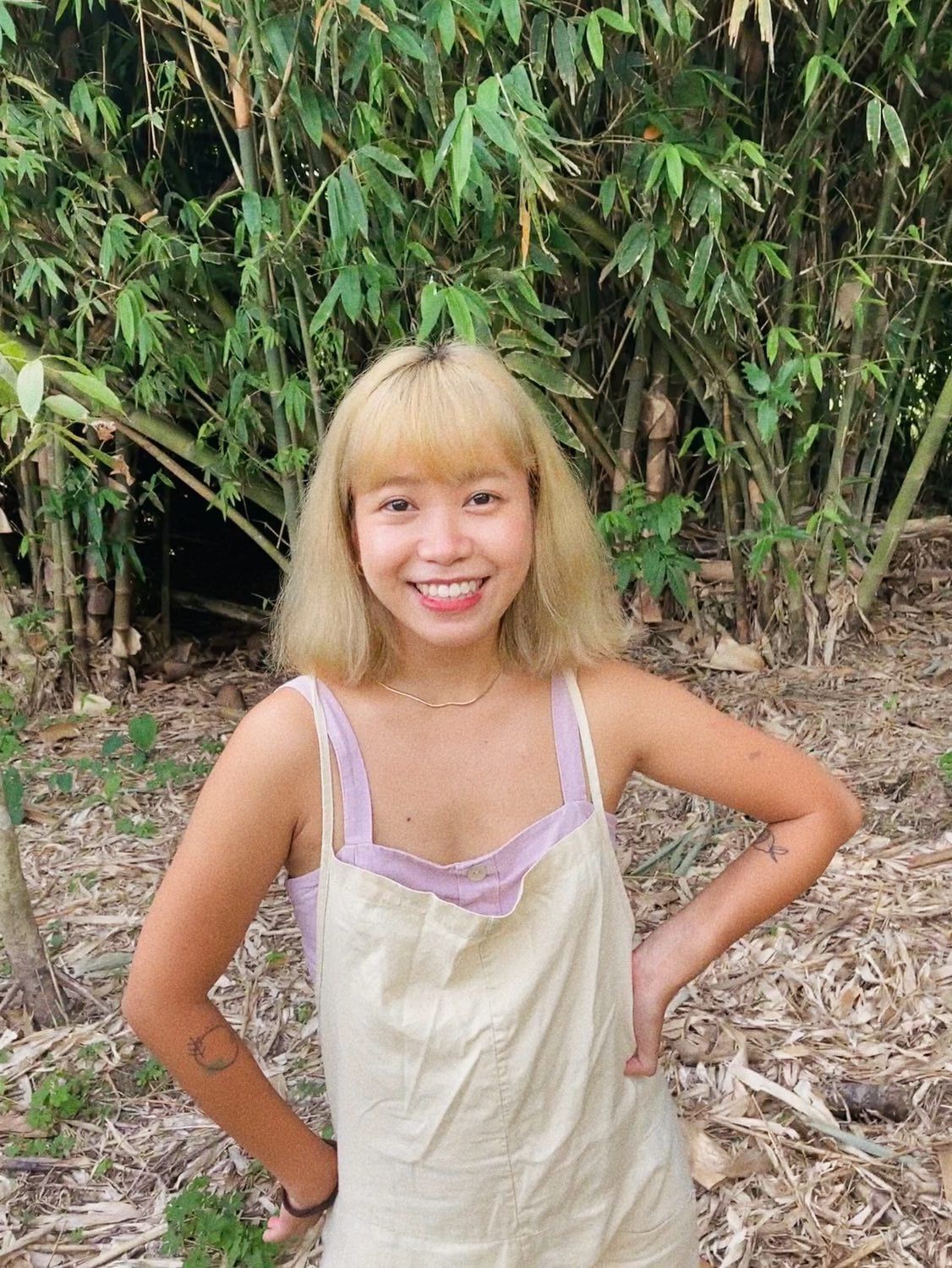 Asian woman with blonde, fringed hair in a field.