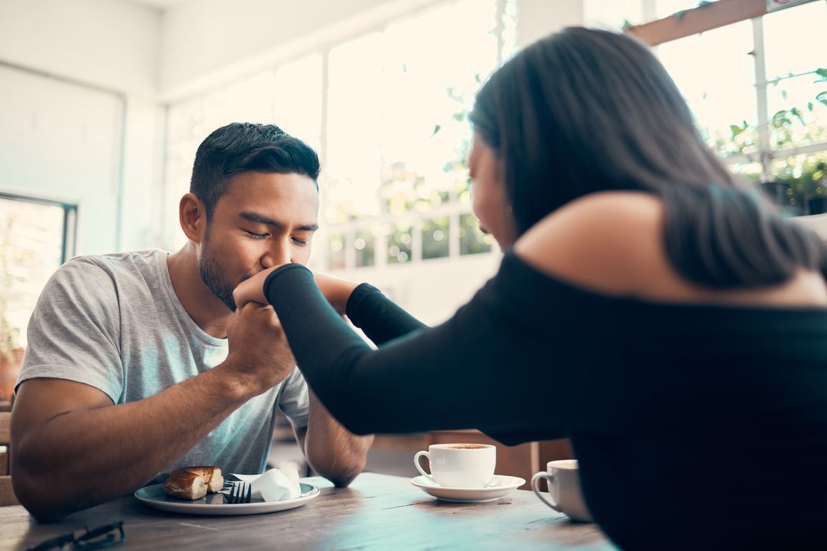 Asian guy kissing the hand of a woman while on a date