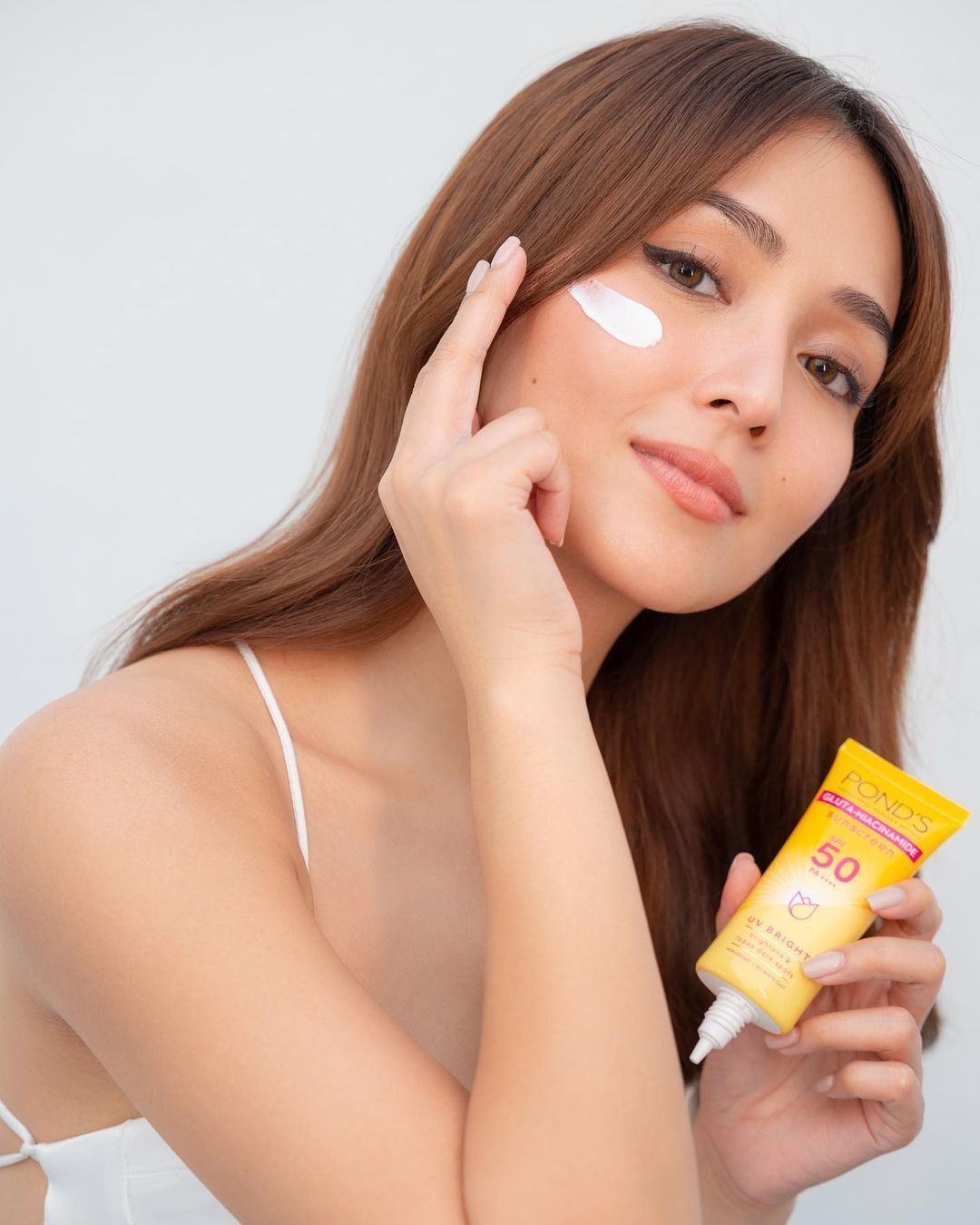 Kathryn Bernardo applying sunscreen on her cheek.