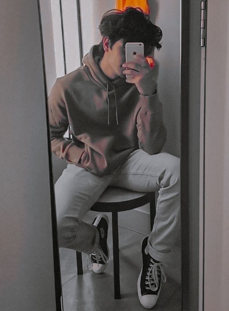 Young man taking his photo in front of a mirror.