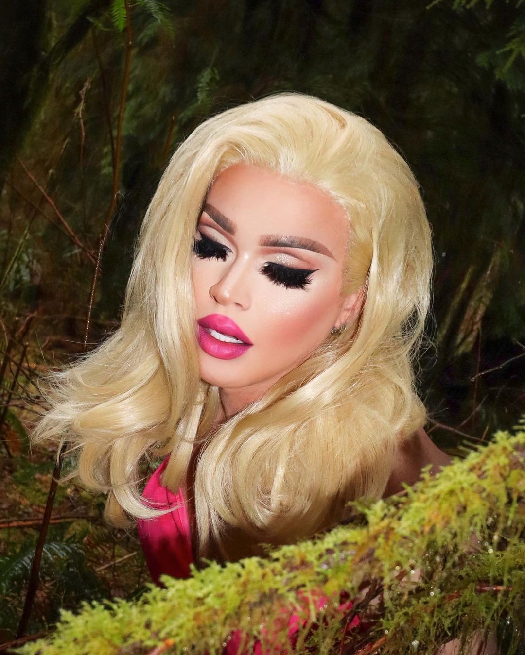 A drag queen with big fake lashes, pink lips, and blonde wig.