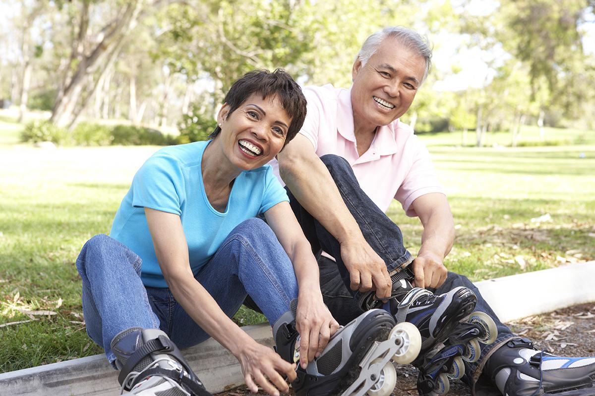 Elderly Asian couple putting on rollerblades