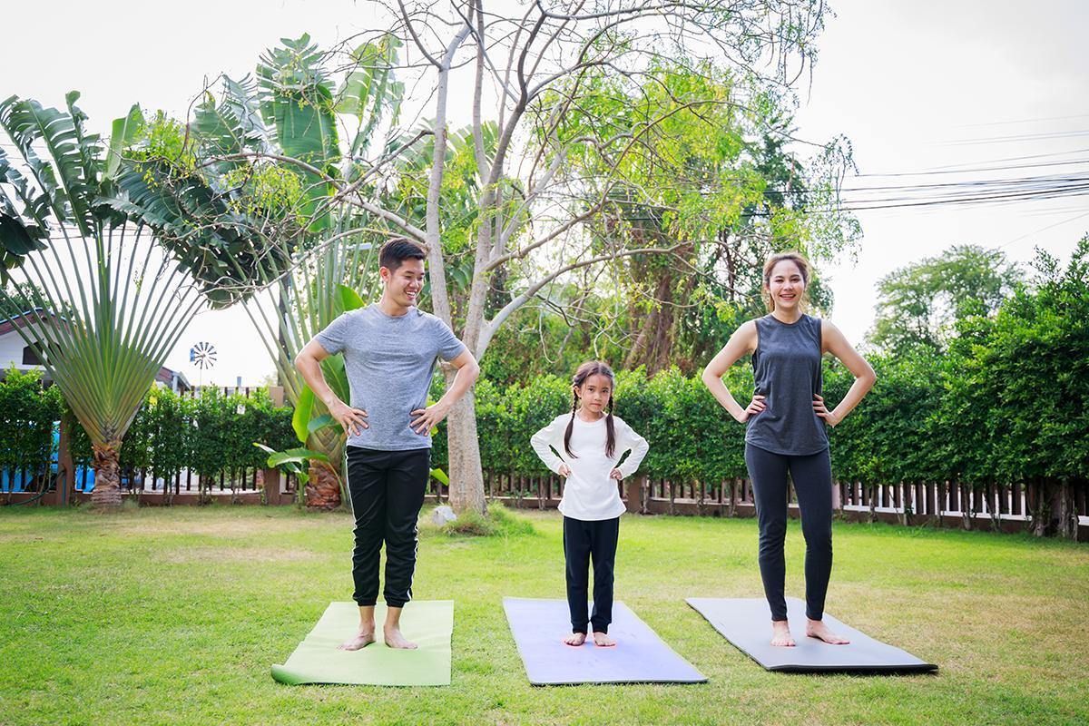 Asian family doing yoga in the yard