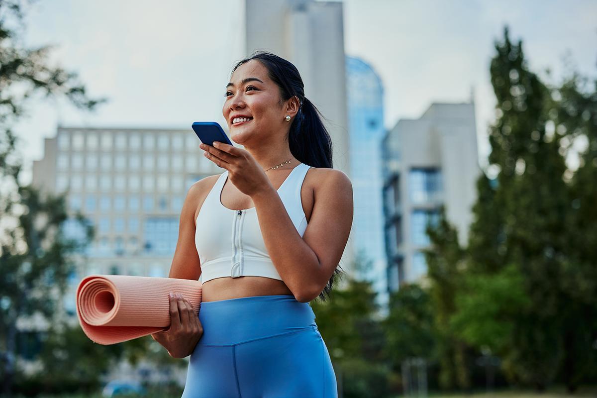 Asian woman in workout gear and carrying a yoga mat