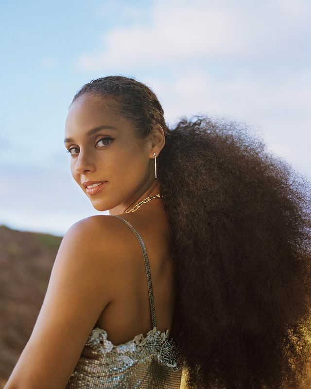 Alicia Keys with curly low ponytail and silver earrings.