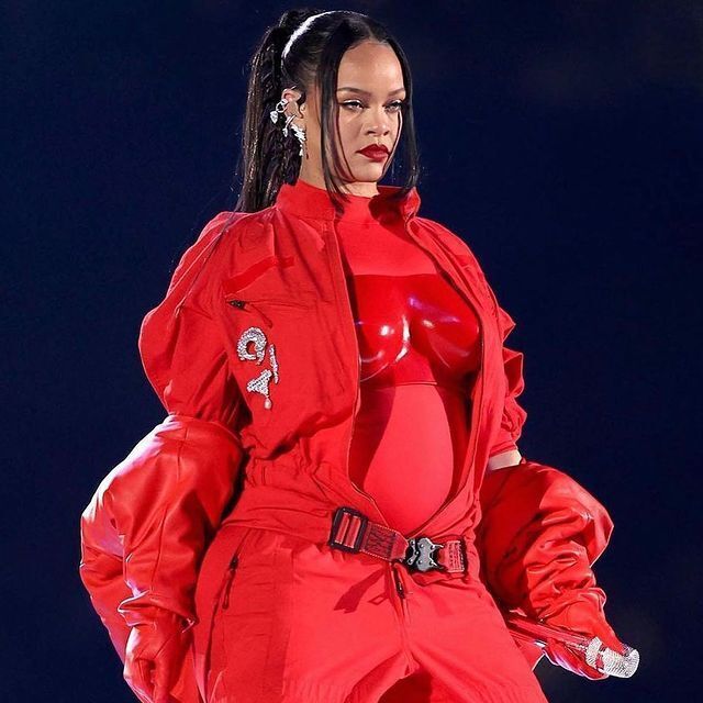 Rihanna wearing a red ensemble and braided ponytail on Super Bowl LVII Halftime Show.