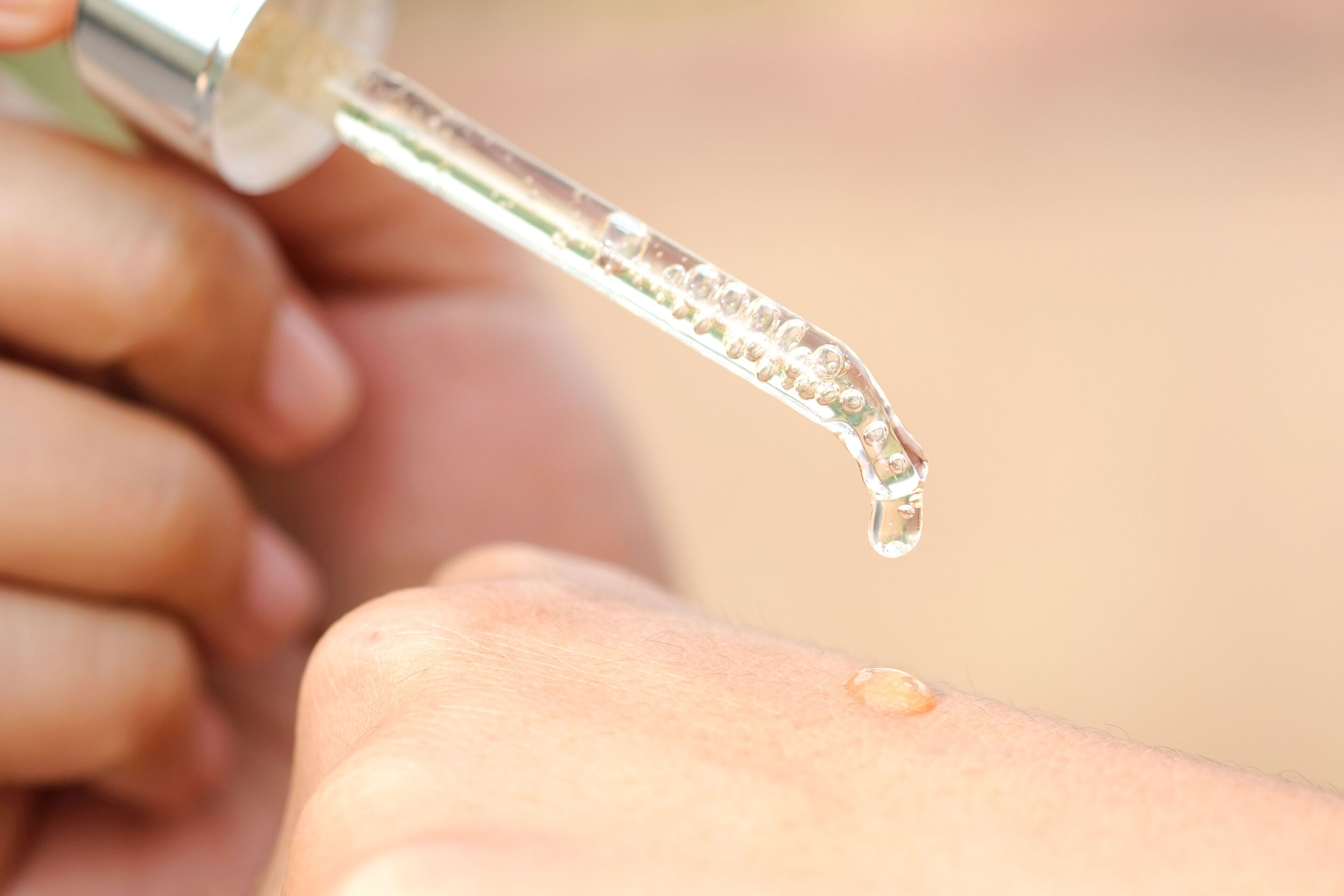 Woman applying serum on her hands with dropper