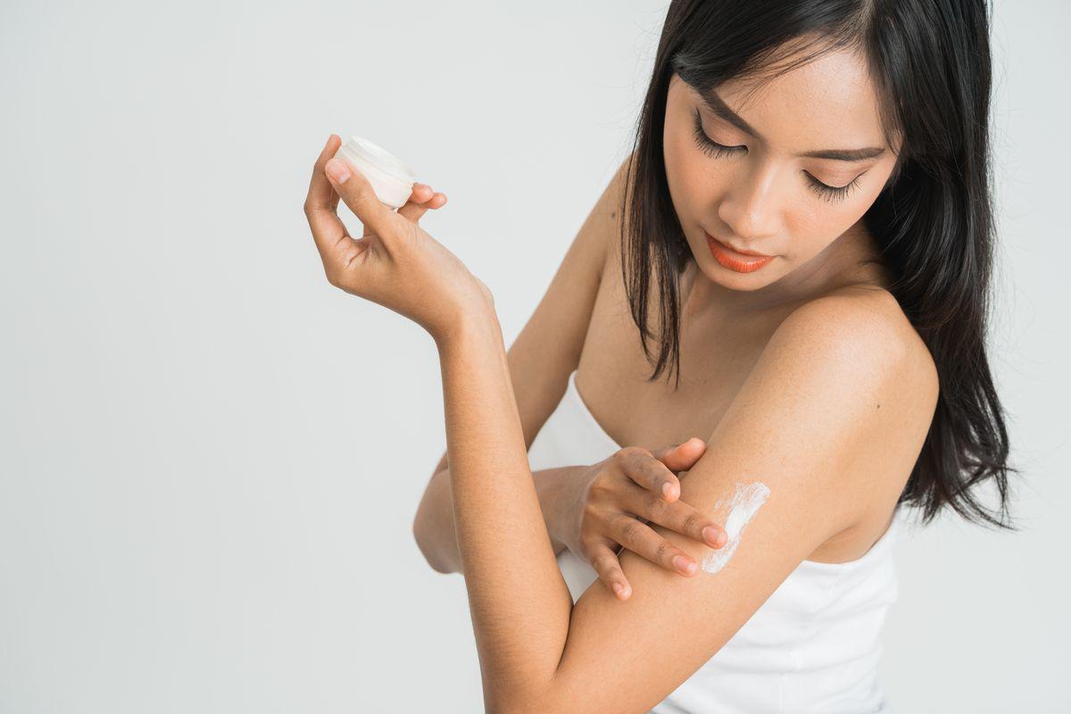 Asian woman applying lotion