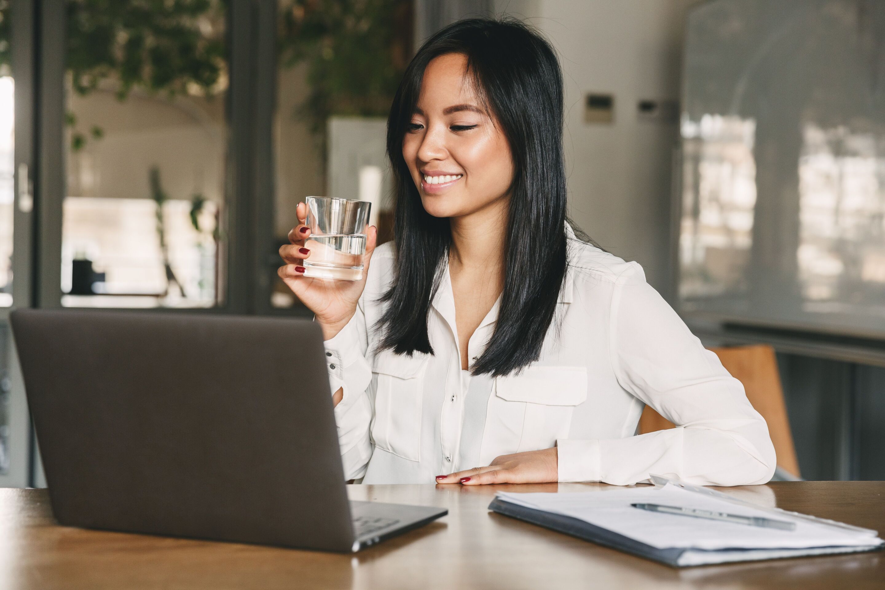A woman holding a glass of water while working