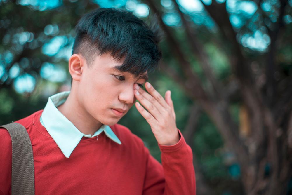 Man rubbing his eyes with his hands.