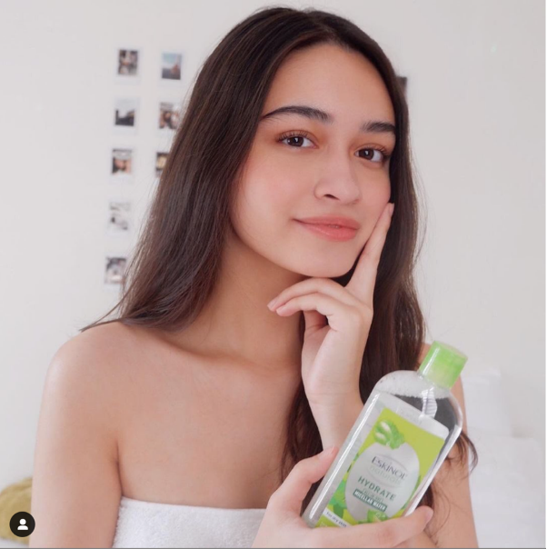 An Asian woman touching face and holding Eskinol Naturals Micellar Water product