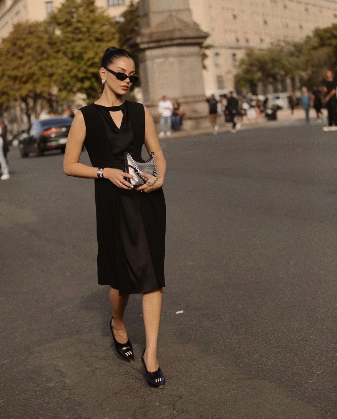 Woman wearing black midi dress and silver purse.