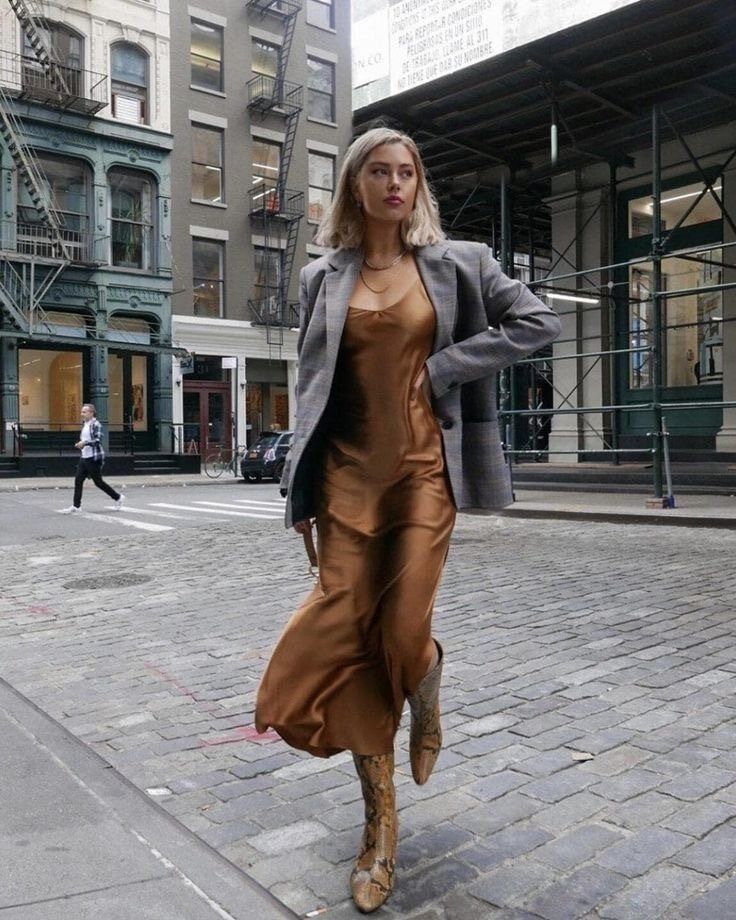 Woman wearing bronze slip dress with gray blazer.