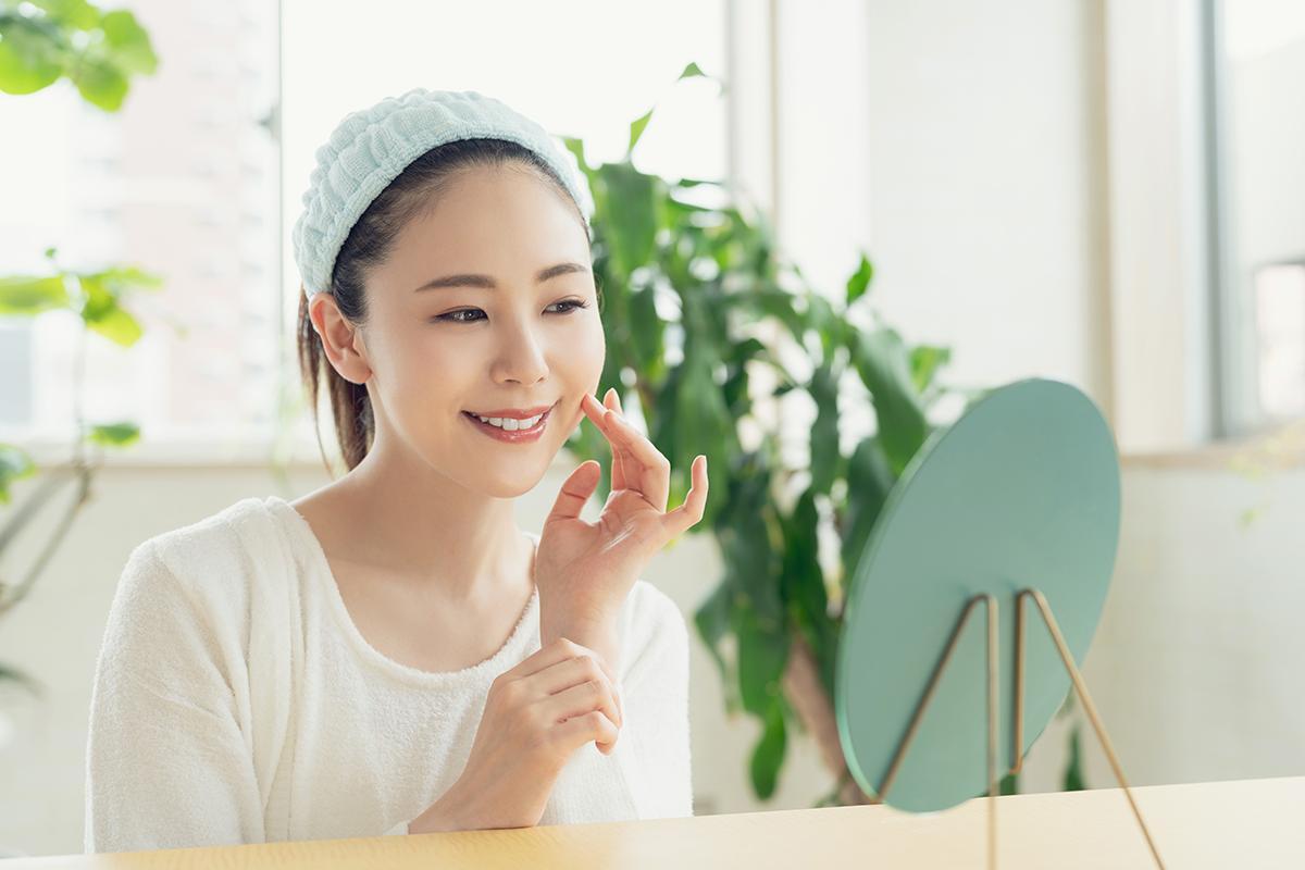An Asian woman applying sunscreen on her face 