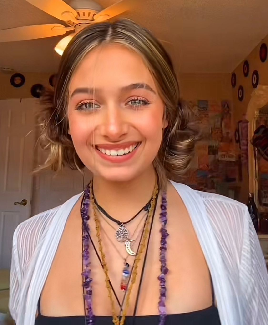 Smiling woman wearing space buns and boho chic necklaces.