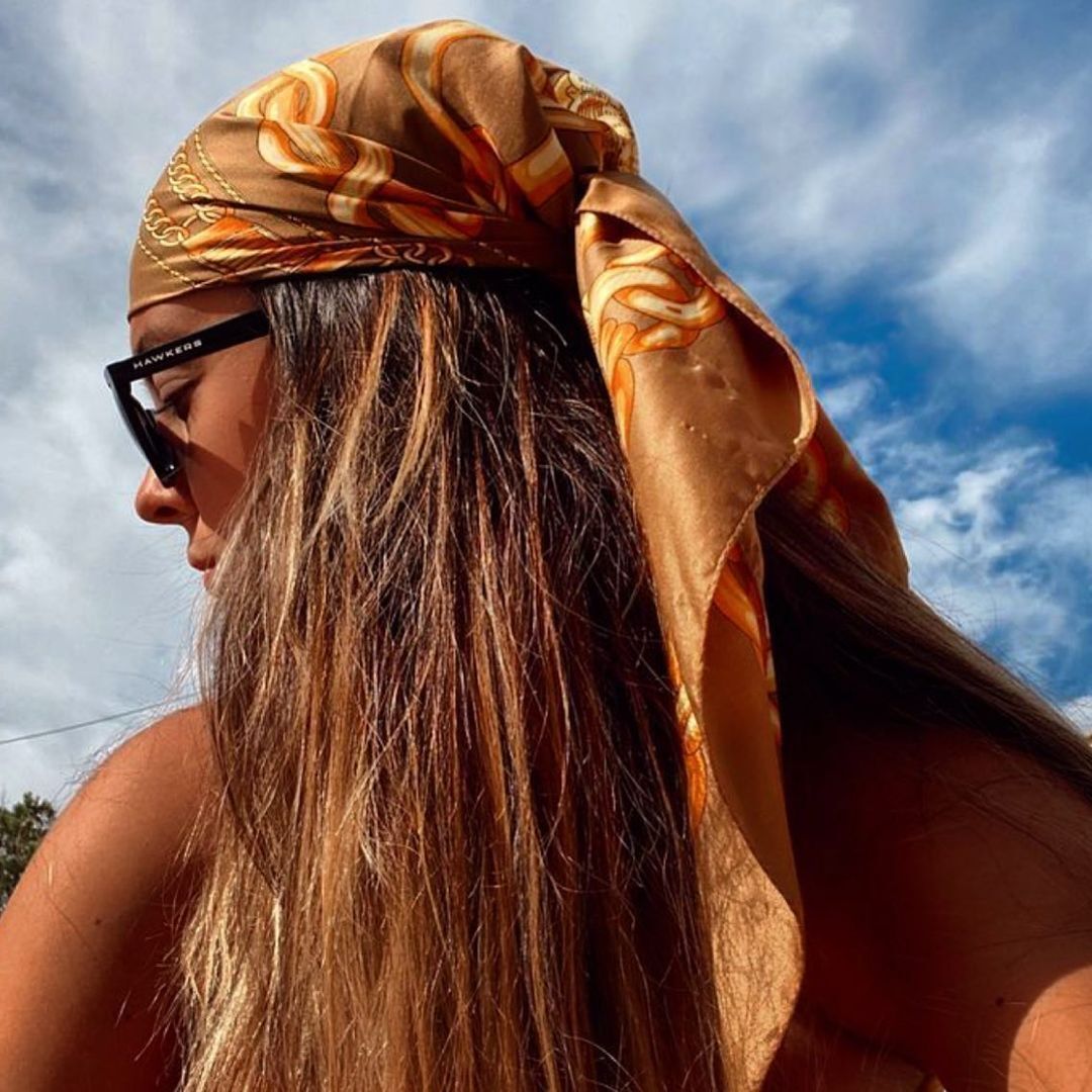 Woman wearing black sunnies and brown head scarf.