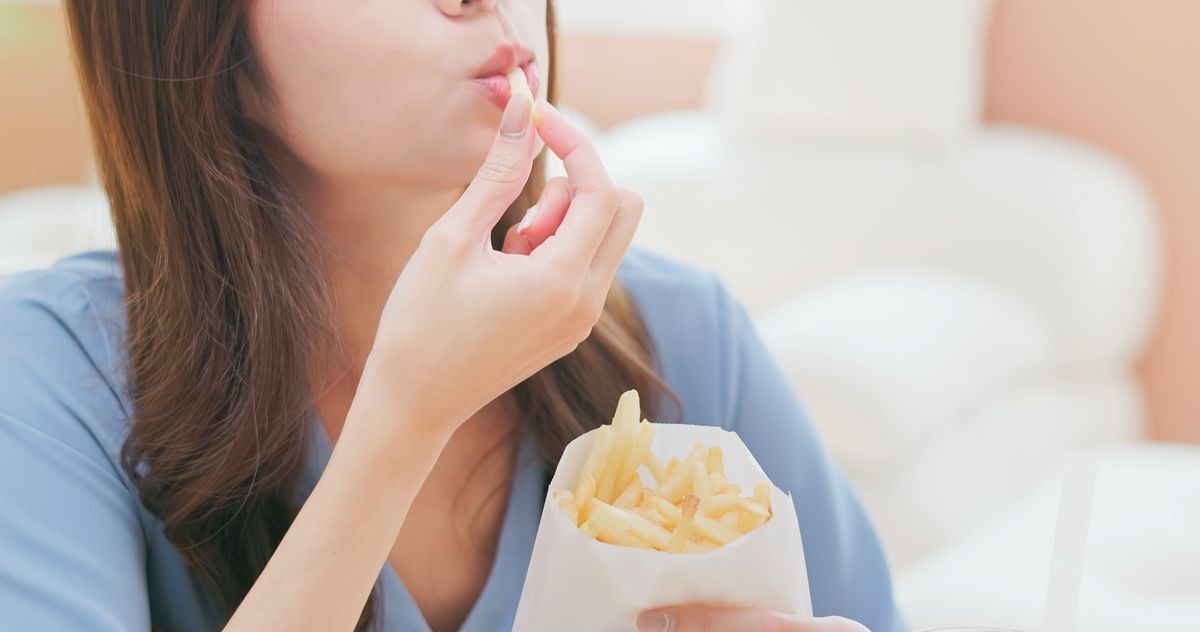 Closeup of a woman eating fries.