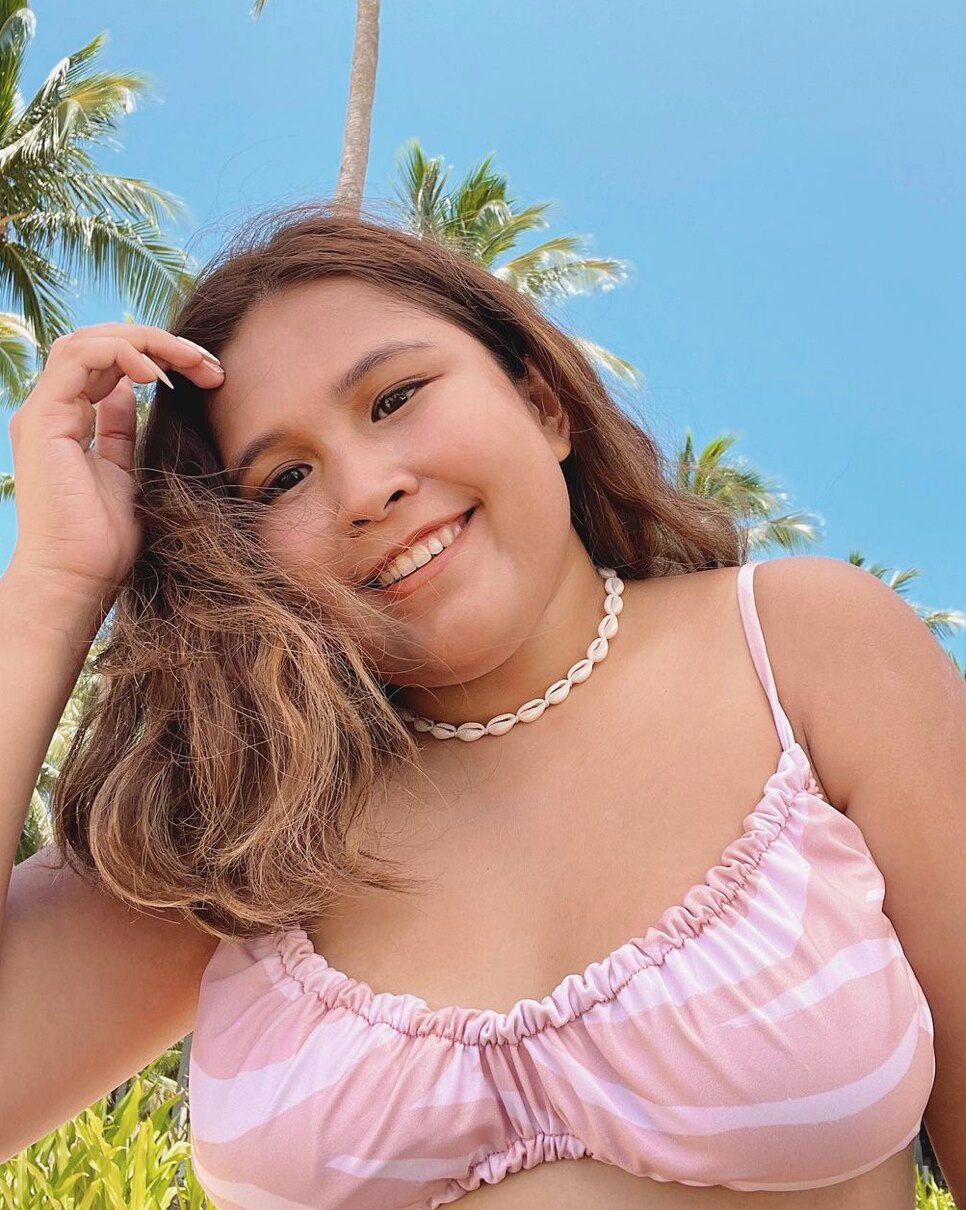 Filipino woman wearing a pink top at the beach.